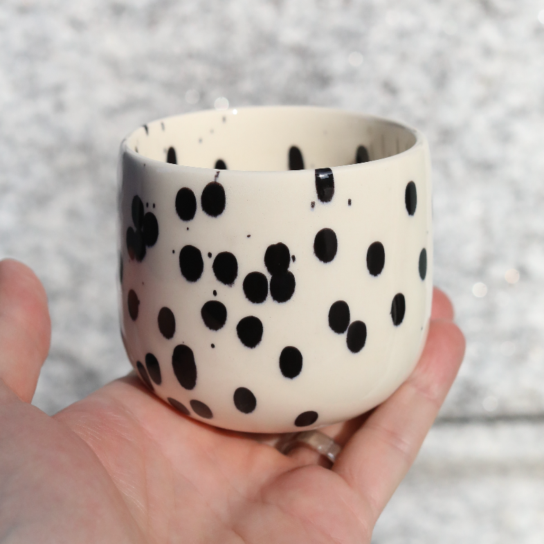 Coffee mug Black Dots for latte macchiato made of stoneware with 280ml held in the hand.