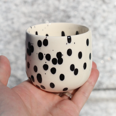 Coffee mug Black Dots for latte macchiato made of stoneware with 280ml held in the hand.
