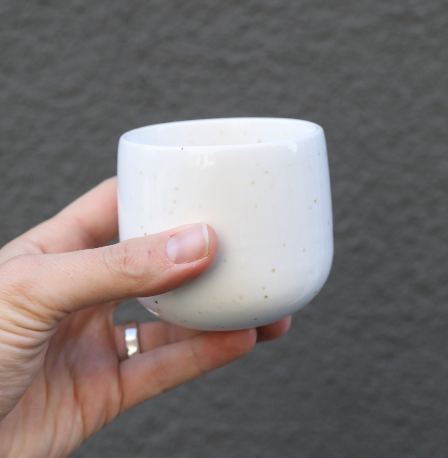 Latte Serra ceramic cup for latte macchiate held in hand against a gray background.