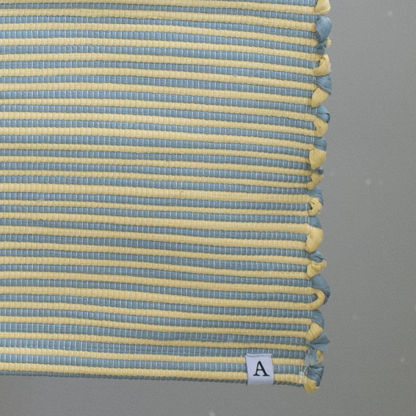 Close-up of a striped two-tone bathroom rug with blue and yellow stripes