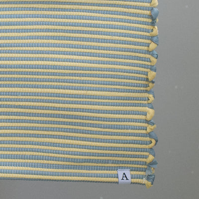 Close-up of a striped two-tone bathroom rug with blue and yellow stripes
