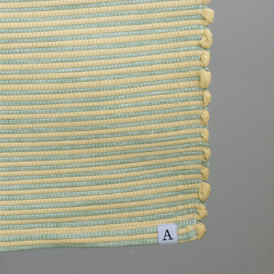 Close-up of a striped two-tone small rug with yellow and green stripes hand-woven in Portugal