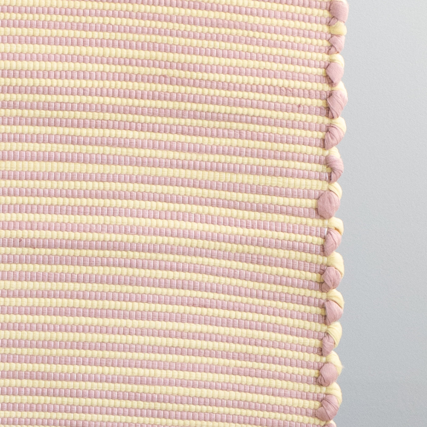Close-up of a striped two-tone small rug with yellow and pink stripes