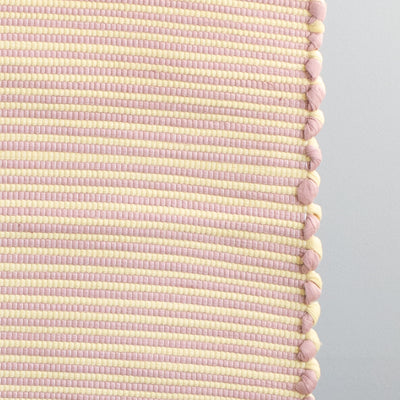 Close-up of a striped two-tone small rug with yellow and pink stripes