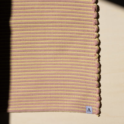 Close-up in the sunlight striped bathroom rug in yellow and pink handwoven from cotton remnants