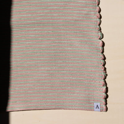Close-up in the sunlight of a striped bathroom rug in pink and mint green