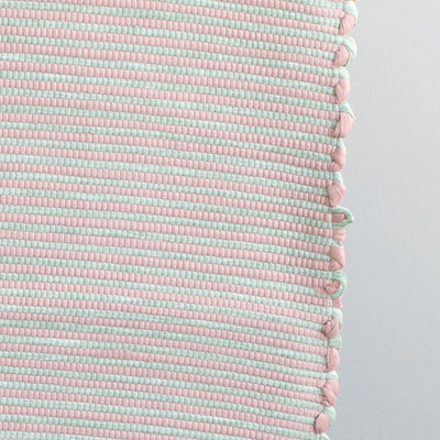 Close-up of a striped two-tone bathroom rug with pink and mint green stripes made from cotton remnants