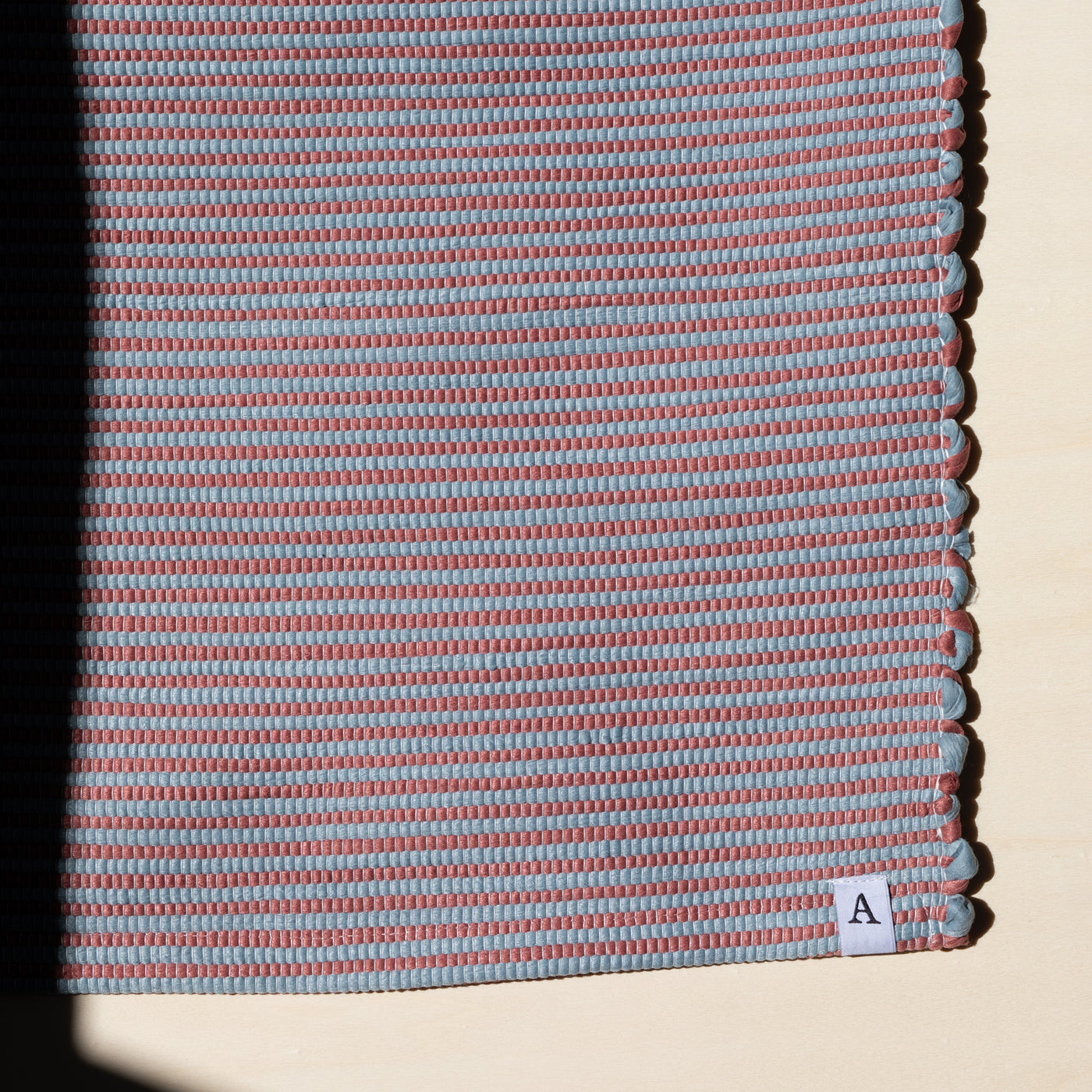 Close-up in sunlight striped small rug 60x90cm in red and blue handmade in Portugal