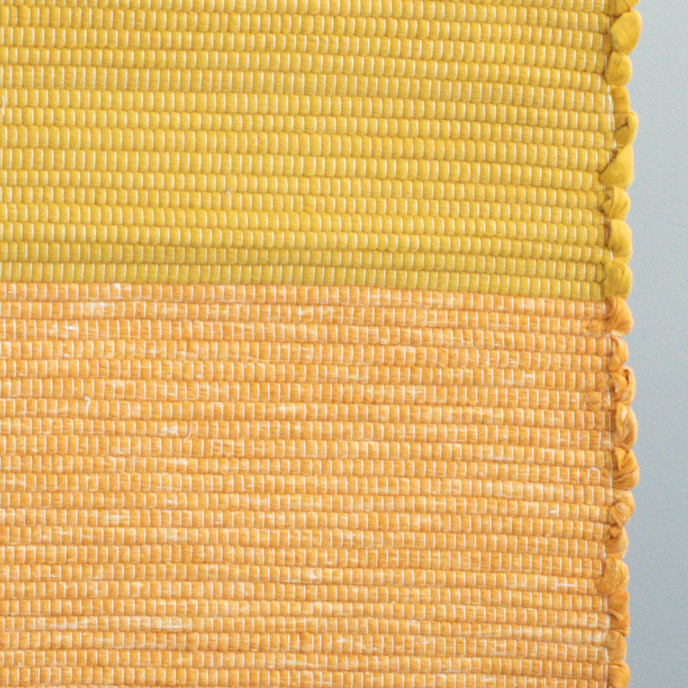 Close-up of the 60x90cm rug made from cotton remnants in orange and yellow