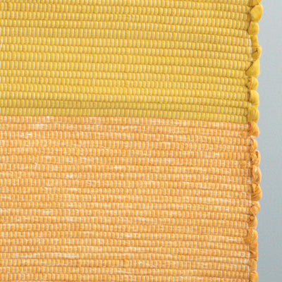 Close-up of the 60x90cm rug made from cotton remnants in orange and yellow