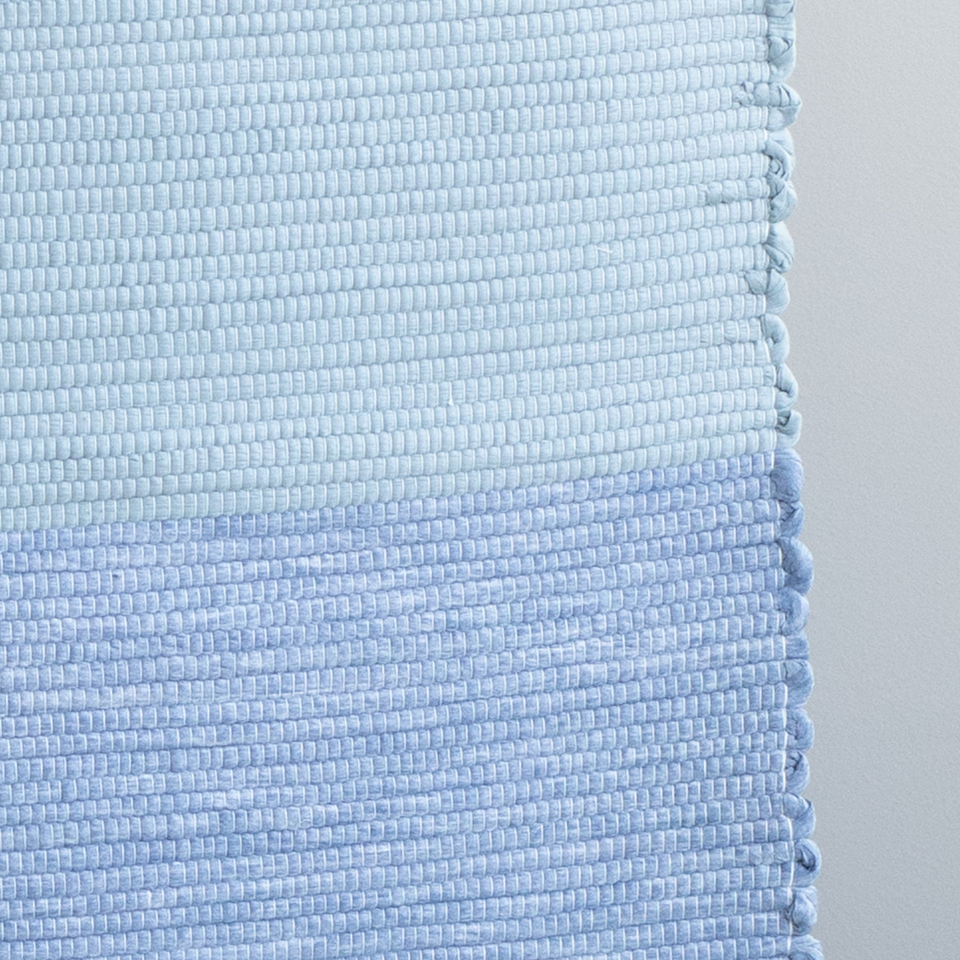 Close-up of a hand-woven light blue and dark blue bathroom rug