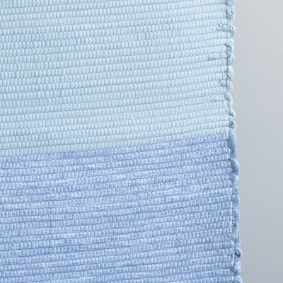Close-up of a hand-woven light blue and dark blue bathroom rug