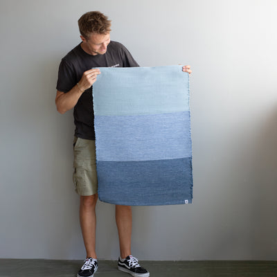 Carpet held by one person with 3 color blocks of different shades of blue