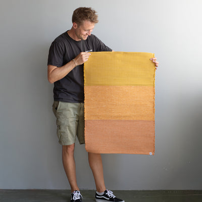 Foot rug held by one person in three colors from light orange to dark orange