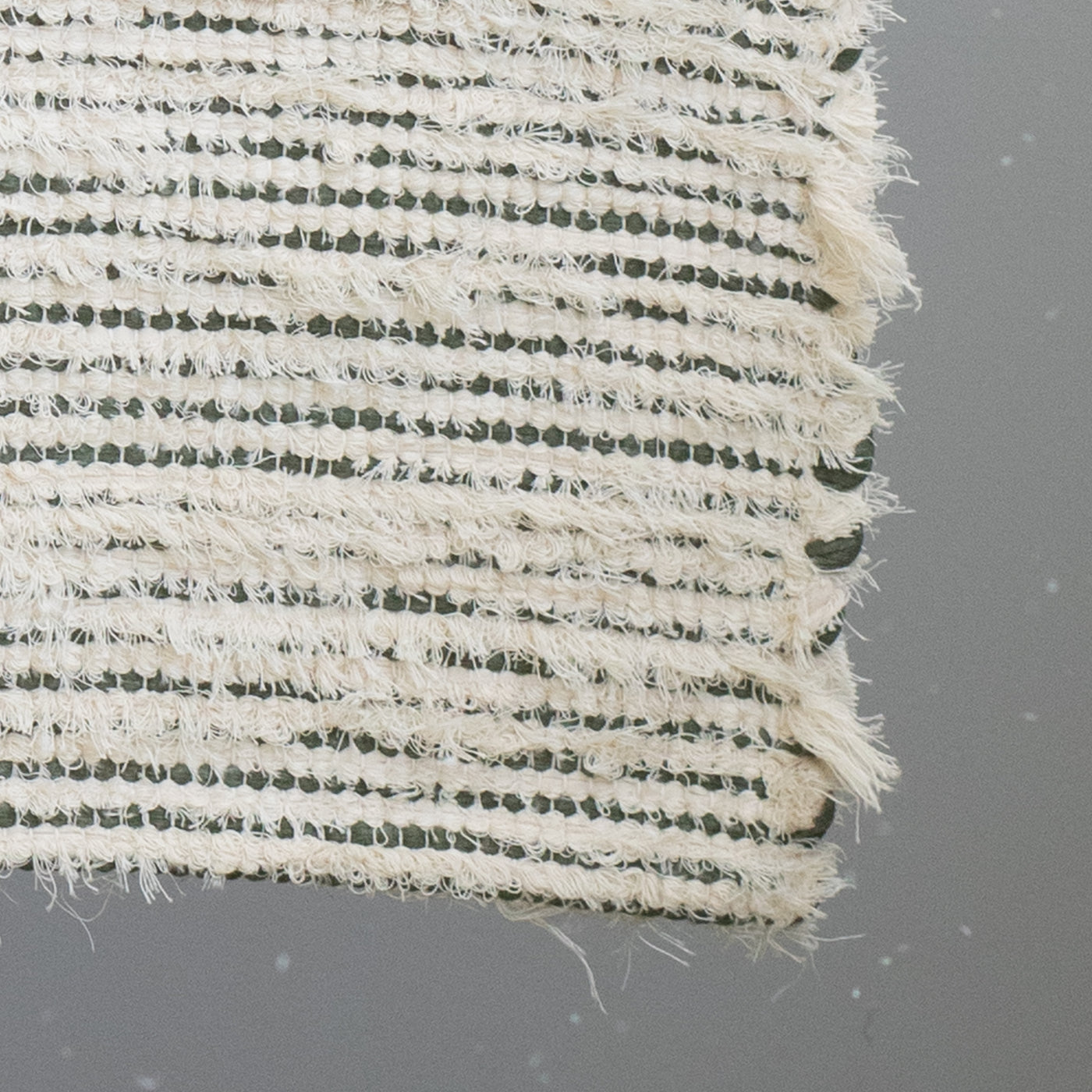 Closeup of a bathroom rug striped with olive green cotton fabric and white terrycloth 