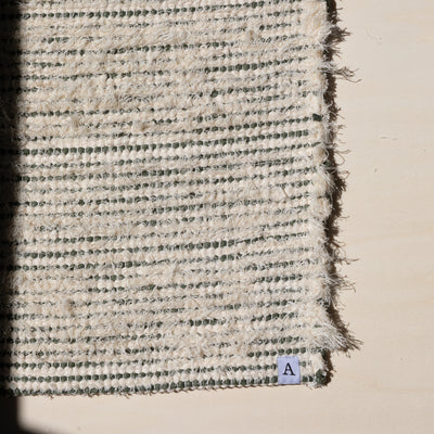 Closeup of a small rug 60x80cm striped with olive green cotton fabric and white terry cloth in the sunlight