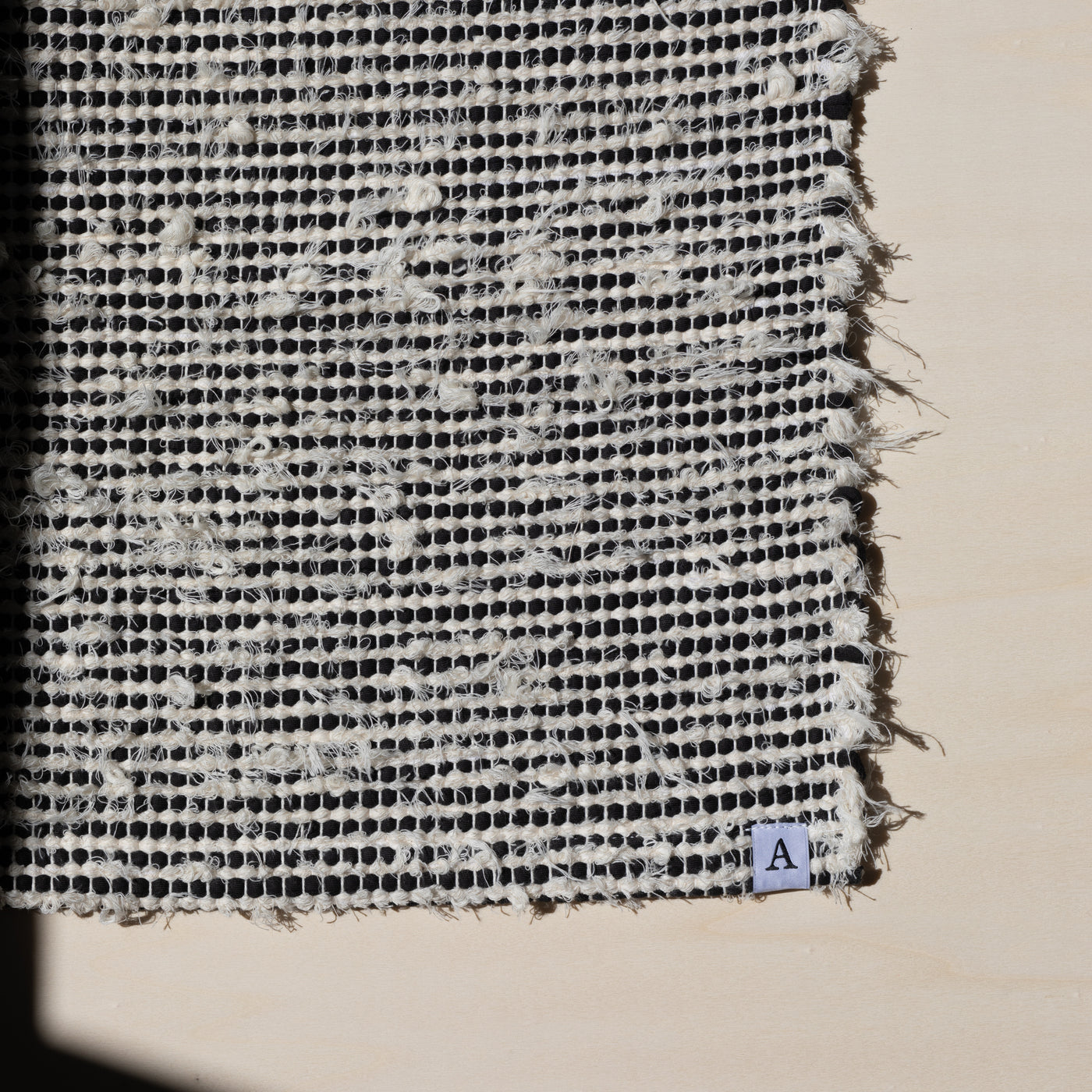 Closeup of a small carpet 60x80cm striped with black cotton fabric and white terry cloth in the sunlight