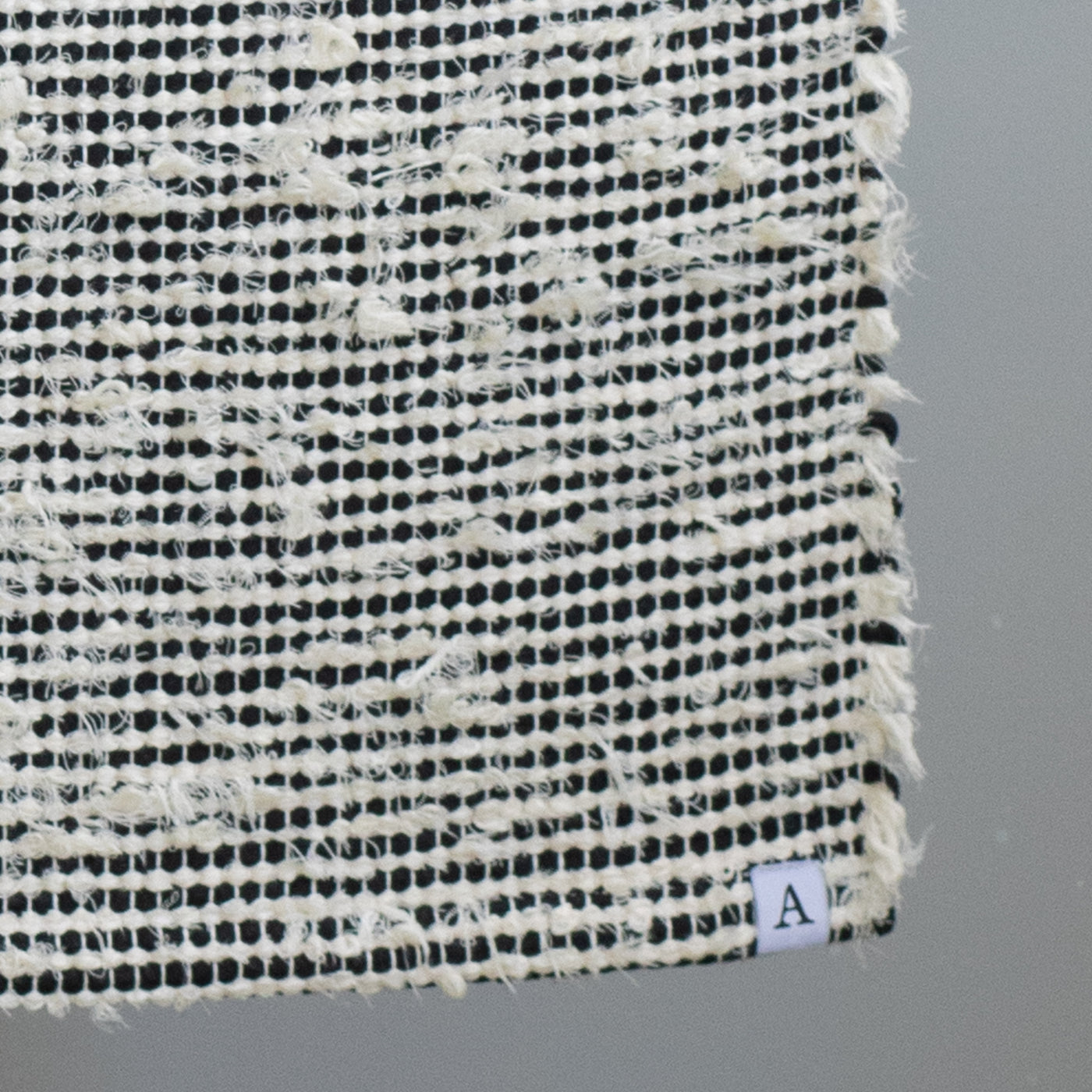 Closeup of a bathroom rug striped with black cotton fabric and white terrycloth 