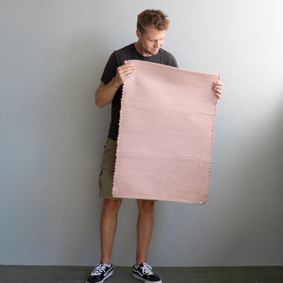 60x90cm small rug held by a person in dusky pink striped with jute hand-woven in Portugal