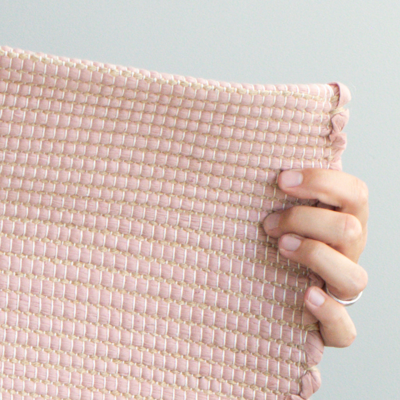 Close-up of a small rug 60x90cm in dusky pink with jute stripes made from wool remnants from the textile industry hand-woven in Portugal