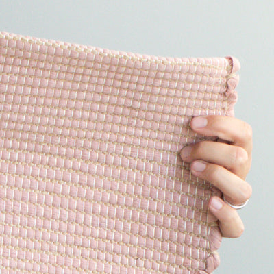 Close-up of a small rug 60x90cm in dusky pink with jute stripes made from wool remnants from the textile industry hand-woven in Portugal