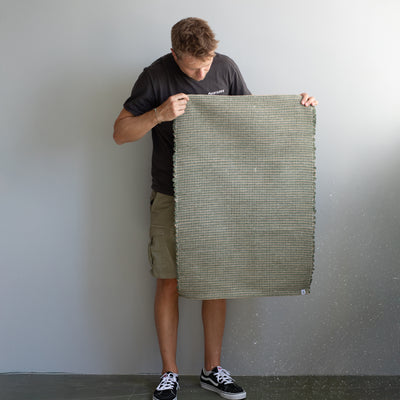 60x90cm small rug held by a person in green striped with jute hand-woven in Portugal