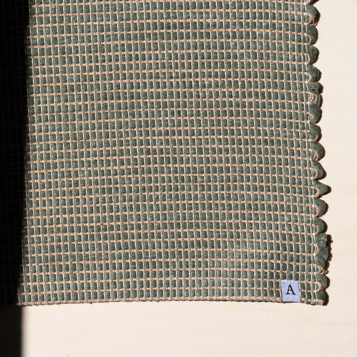 Close-up of a small rug 60x90cm in green interwoven with jute hand-woven from upcycled cotton in Portugal