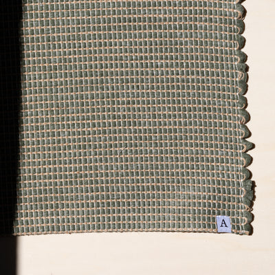 Close-up of a small rug 60x90cm in green interwoven with jute hand-woven from upcycled cotton in Portugal