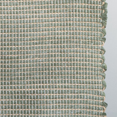 Close-up of a bathroom rug in green with jute stripes made from wool remnants from the textile industry, hand-woven in Portugal