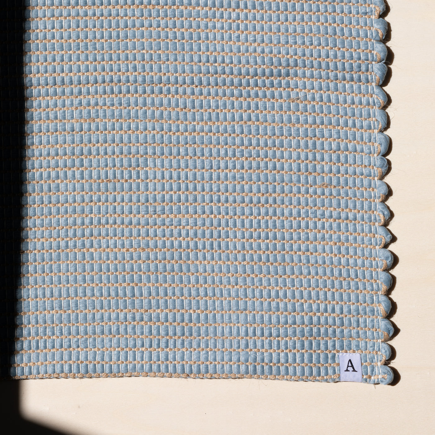 Close-up of a small rug 60x90cm in light blue interwoven with jute hand-woven from upcycled cotton in Portugal