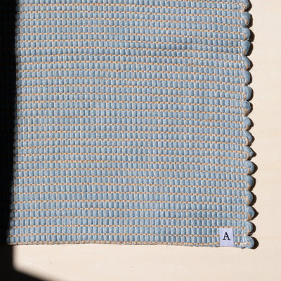 Close-up of a small rug 60x90cm in light blue interwoven with jute hand-woven from upcycled cotton in Portugal