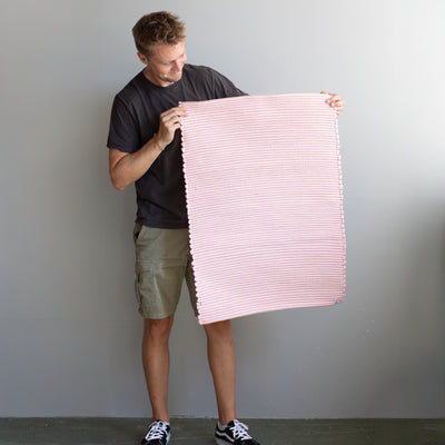 60x90cm small rug held by a person in pink striped with jute hand-woven in Portugal