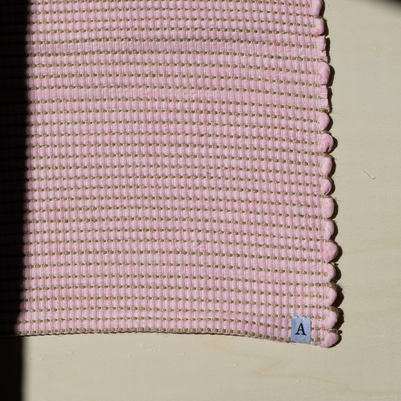 Close-up of a small rug 60x90cm in pink interwoven with jute hand-woven from upcycled cotton in Portugal