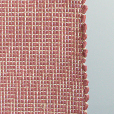 Close-up of a bathroom rug in red with jute stripes made from wool remnants from the textile industry, hand-woven in Portugal