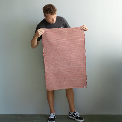 60x90cm small rug held by a person in red striped with jute hand-woven in Portugal