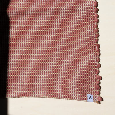 Close-up of a small rug 60x90cm in red interwoven with jute hand-woven from upcycled cotton in Portugal