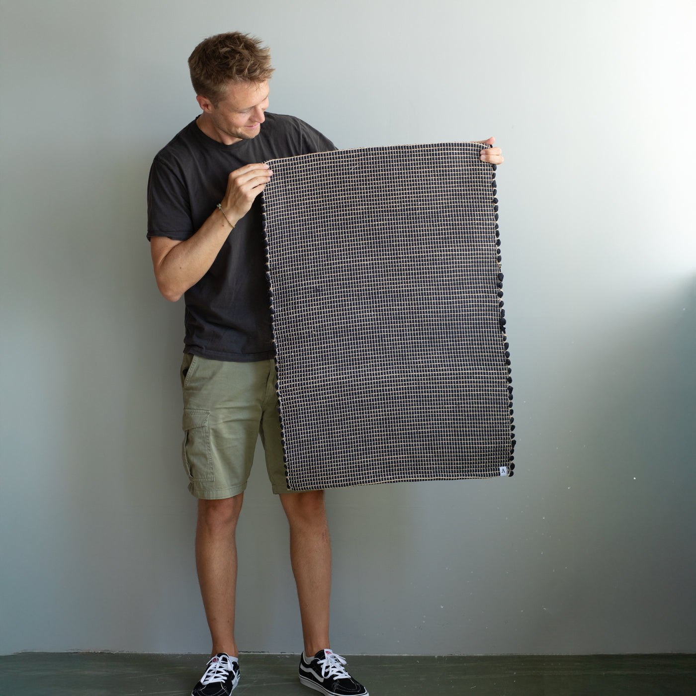 60x90cm small rug held by a person in black striped with jute hand-woven in Portugal