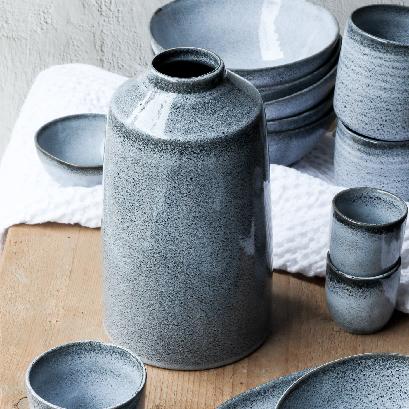 Blue Bottle flower vase stands in the center of the Blue Sand tableware line next to espresso cups, pasta plates and bowls