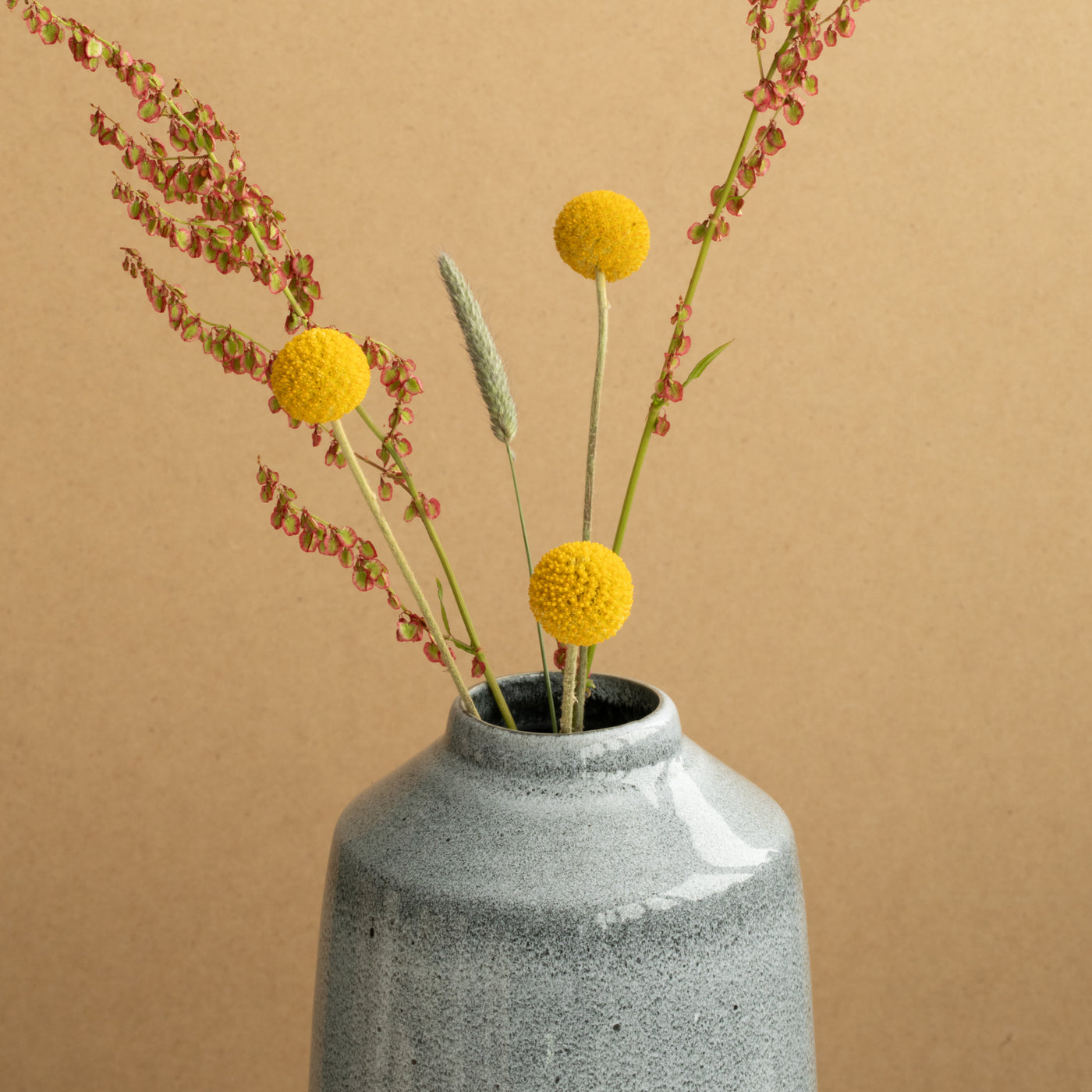 Close-up of the small opening of the blue flower vase with some yellow flowers