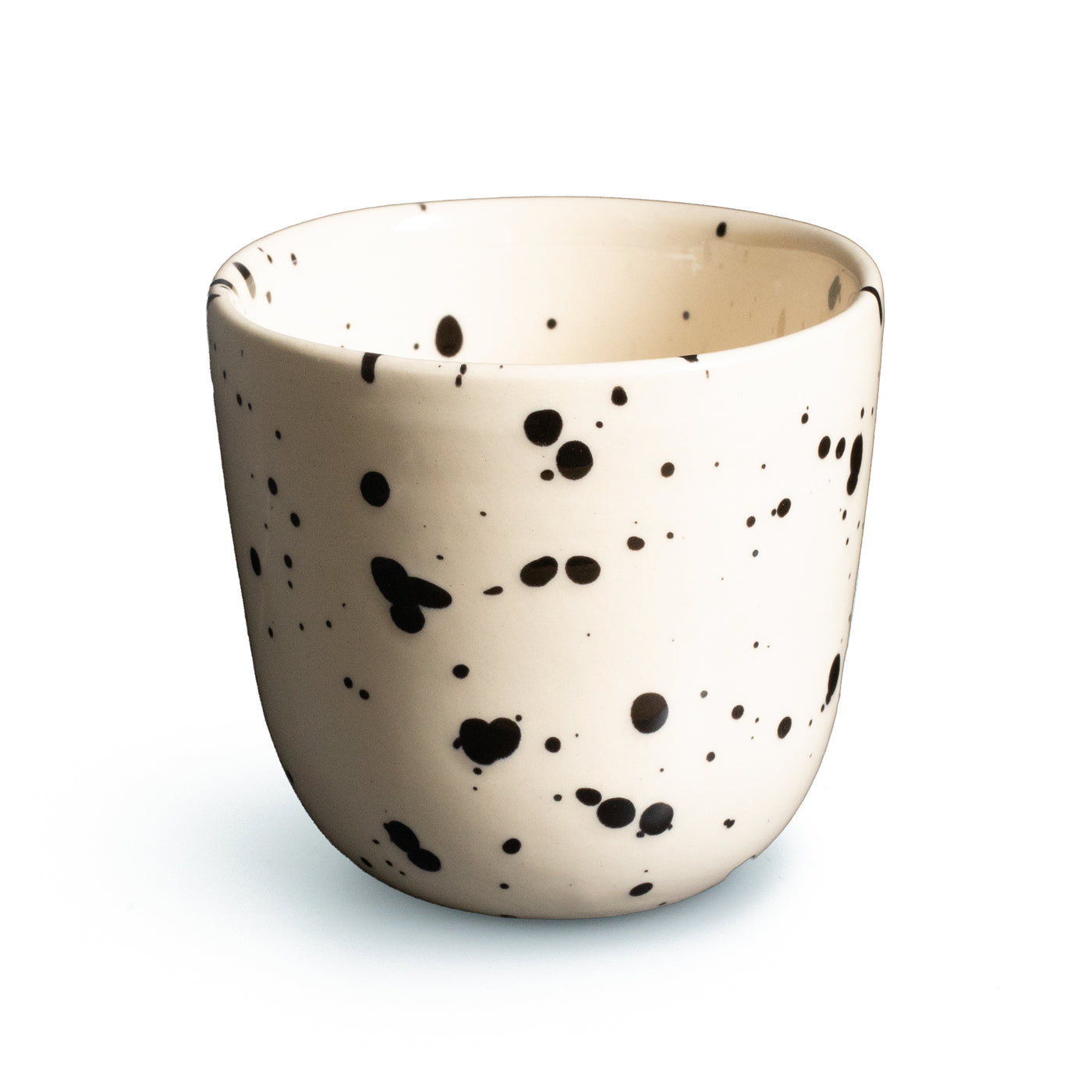 Beige coffee cup with black dots cropped against a white background