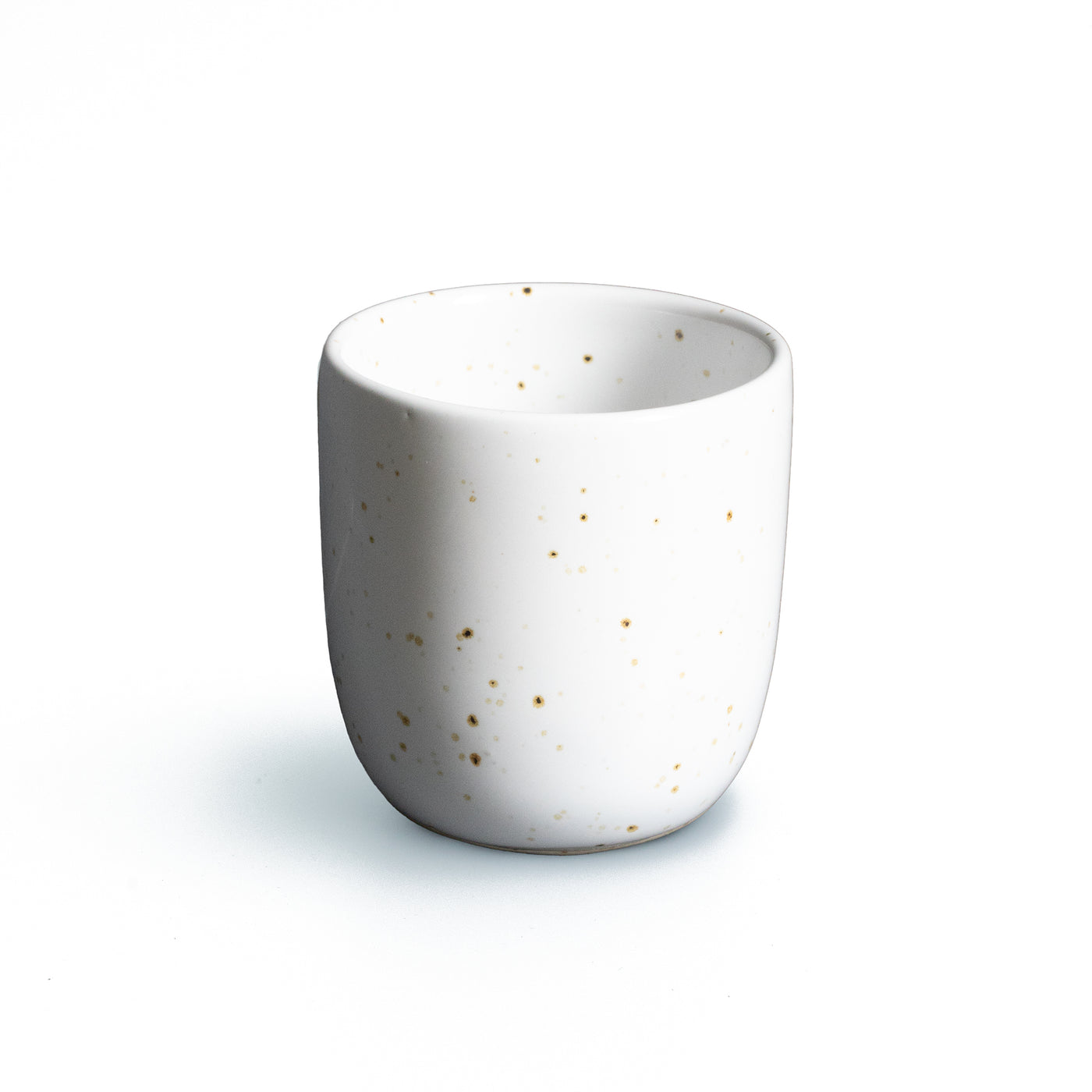 Espresso cup without handle in white with golden sprinkles against a white background