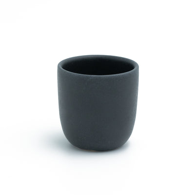 Matte black espresso cup without handle cropped against a white background