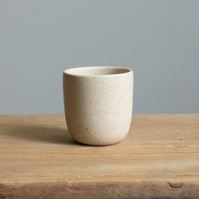 Matt beige espresso cup on a wooden table seen from the front