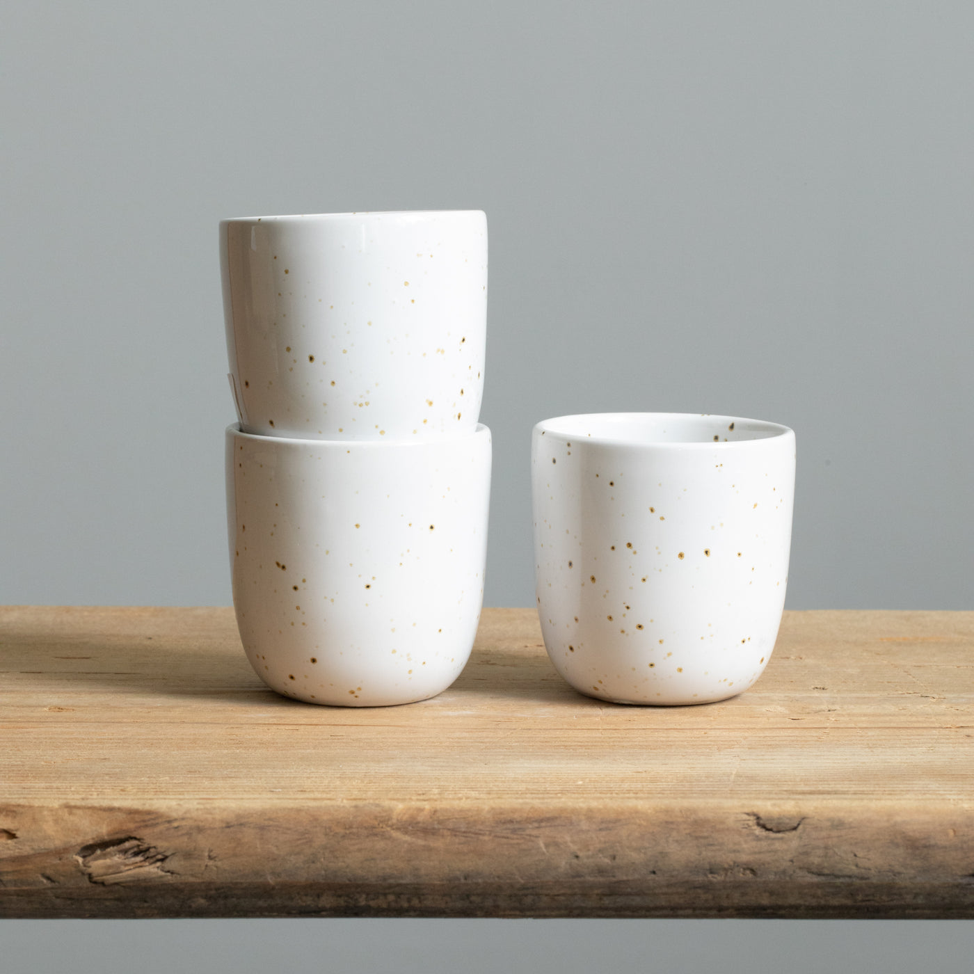 Three stacked white espresso cups with fine golden sprinklers