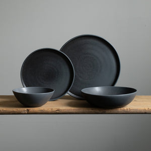 Complete tableware set in matt black color includes a large and small plate, muesli bowl and a pasta plate all made of stoneware in Portugal