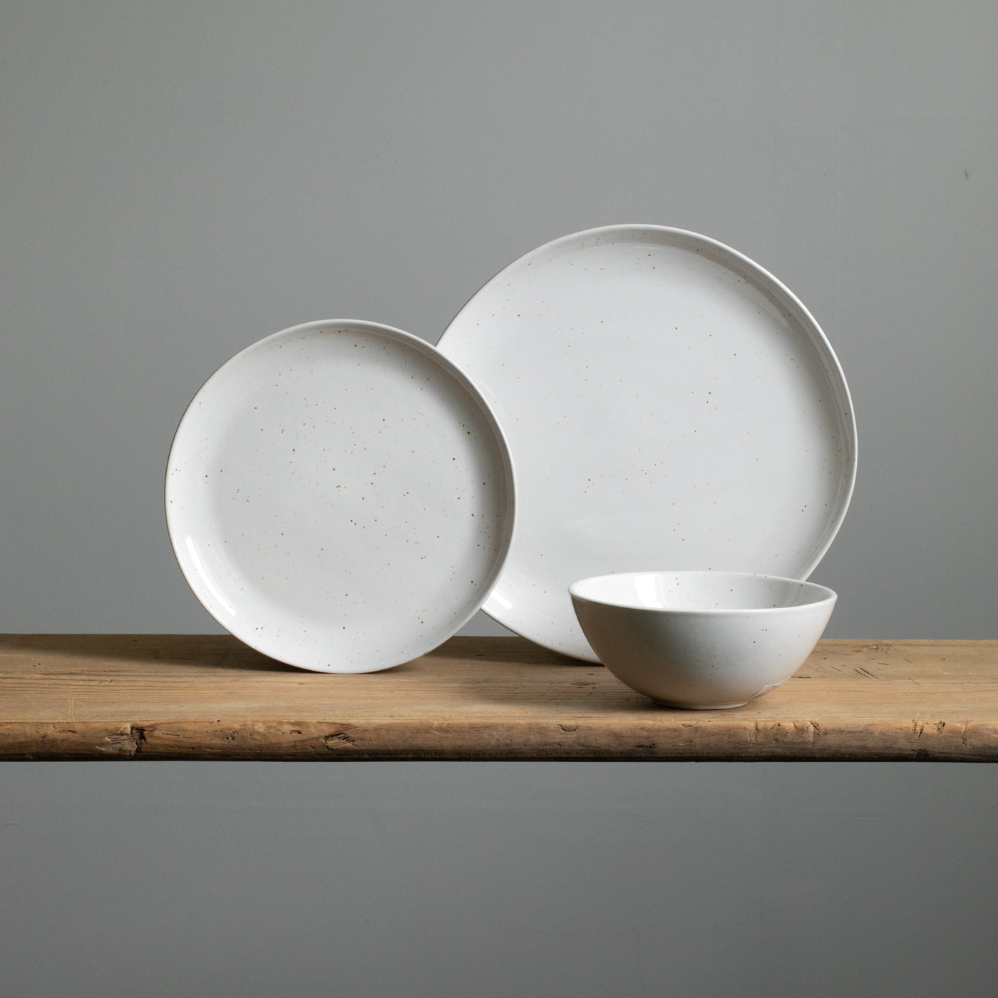 A small stoneware plate next to a main course plate and a white muesli bowl in front of it