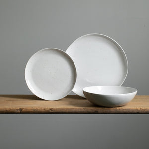 You can see a large main course plate and a small starter plate placed in front of a deep pasta plate with white glaze