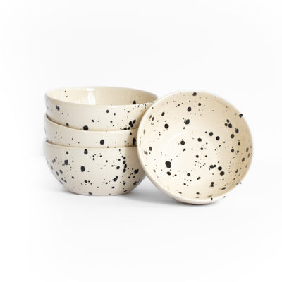 Three stacked and one placed large bowl for snacks in beige color with black dots against a white background