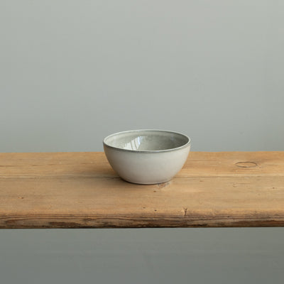 An aperitif bowl on a wooden table made of light gray glazed stoneware