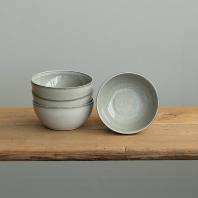 Three light gray snack bowls stacked on top of each other and a bowl placed next to them